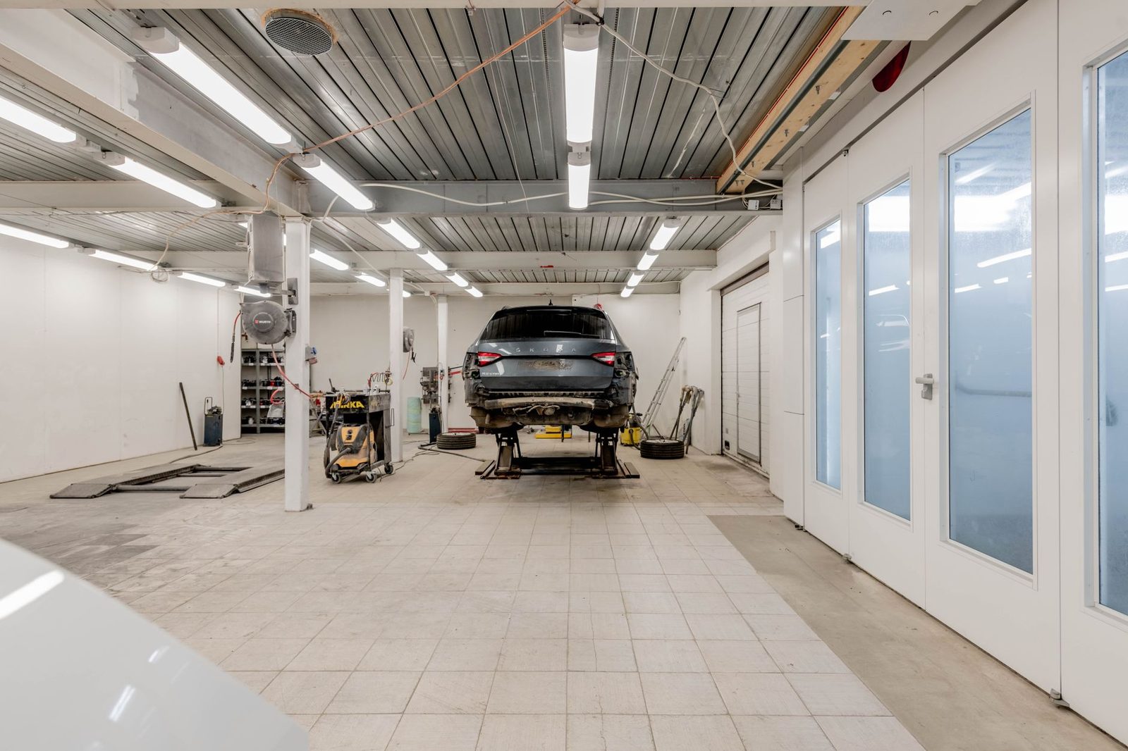 A car raised on a hydraulic lift in a well-lit garage, ready for repair.