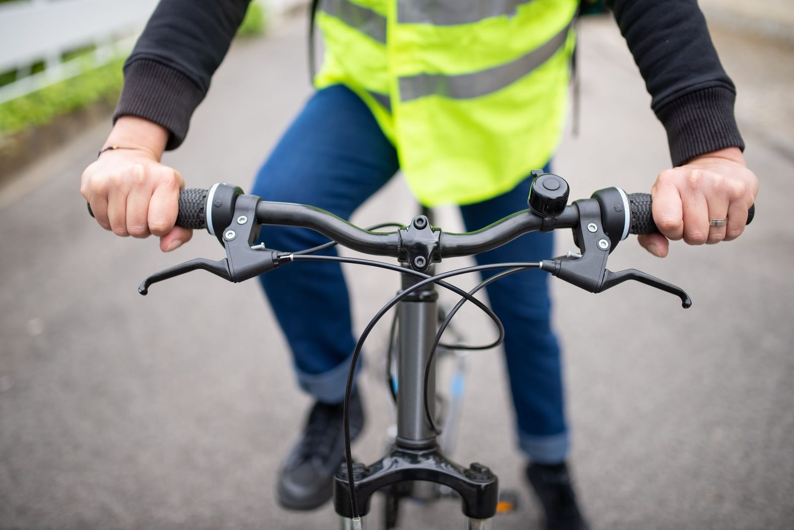 A cyclist in a reflective vest holds the handlebars on a city street in Portugal.