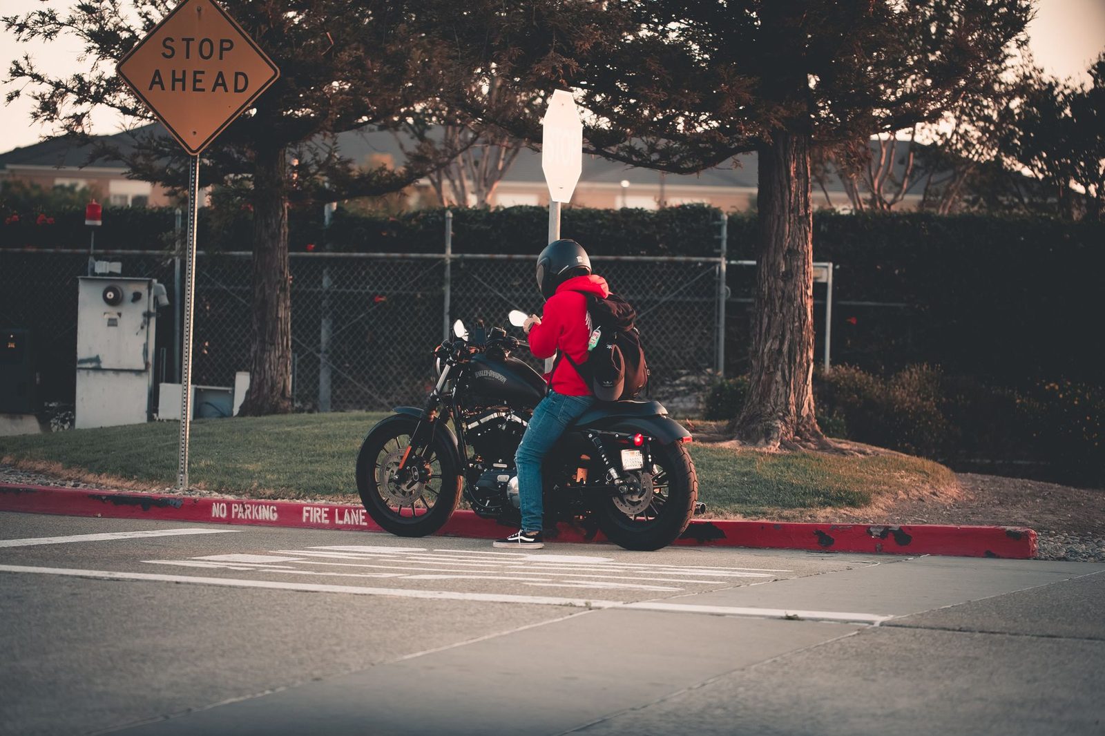 A motorcyclist in a red jacket stops at a stop sign on a San Francisco street.