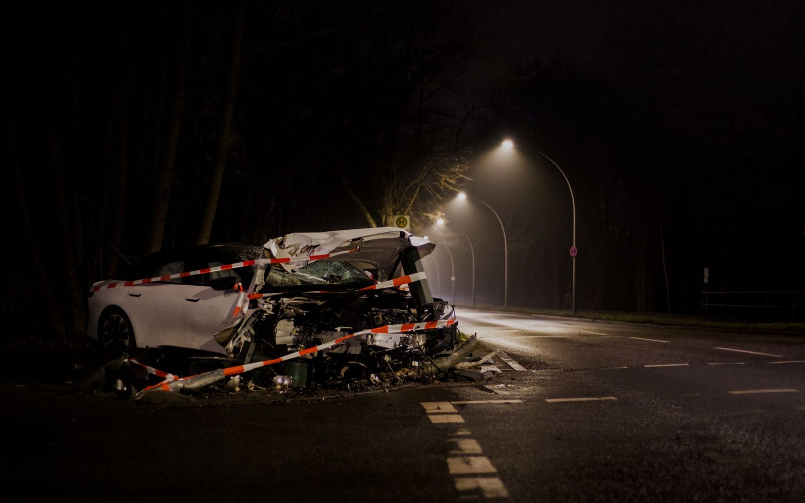 A wrecked car on a dimly lit street in Berlin at night after a collision.
