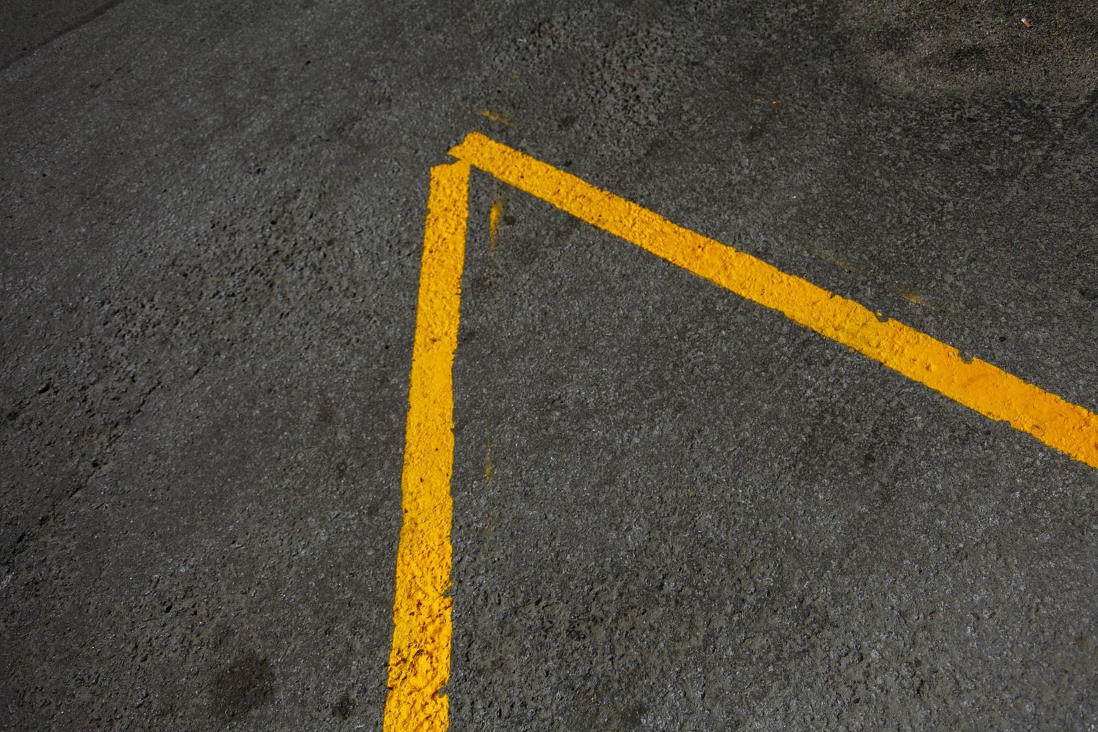 Aerial view of an asphalt road with yellow lane markings in daylight.
