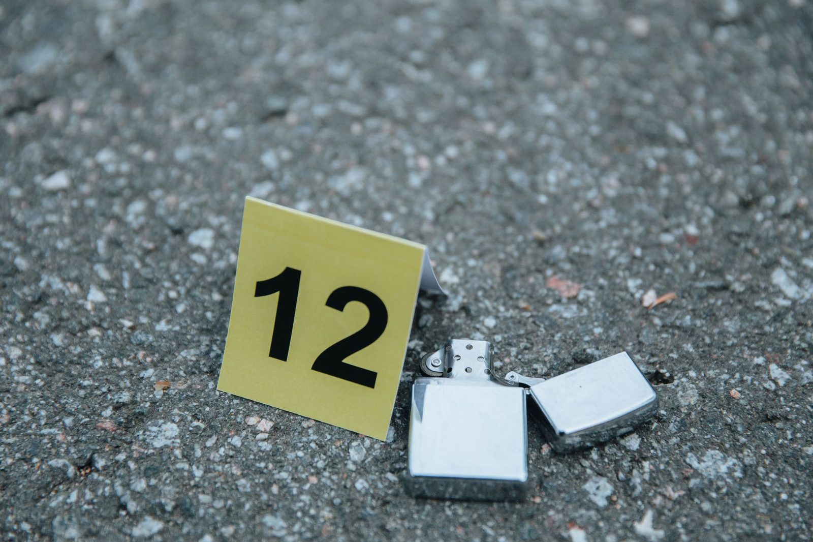 Close-up of a lighter beside a numbered evidence marker on a concrete surface