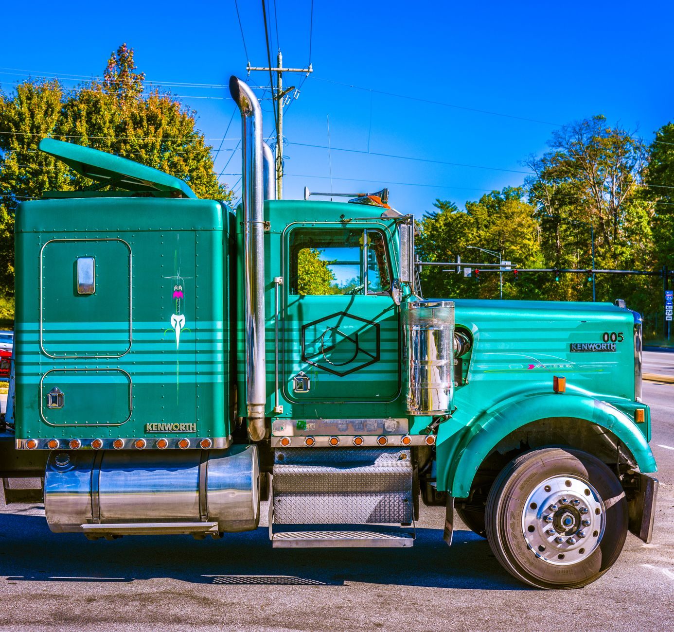 Green Kenworth truck parked outdoors on a sunny day.
