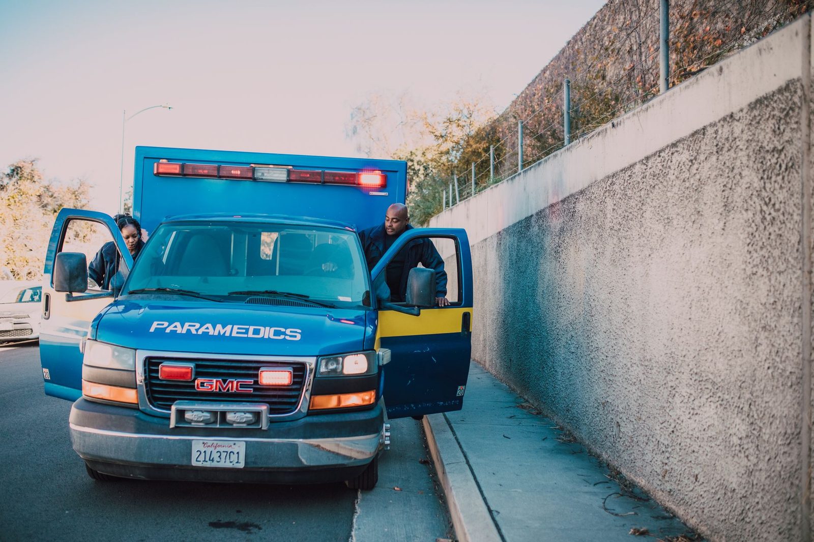 Paramedics tend to a patient at a roadside emergency beside a GMC ambulance.