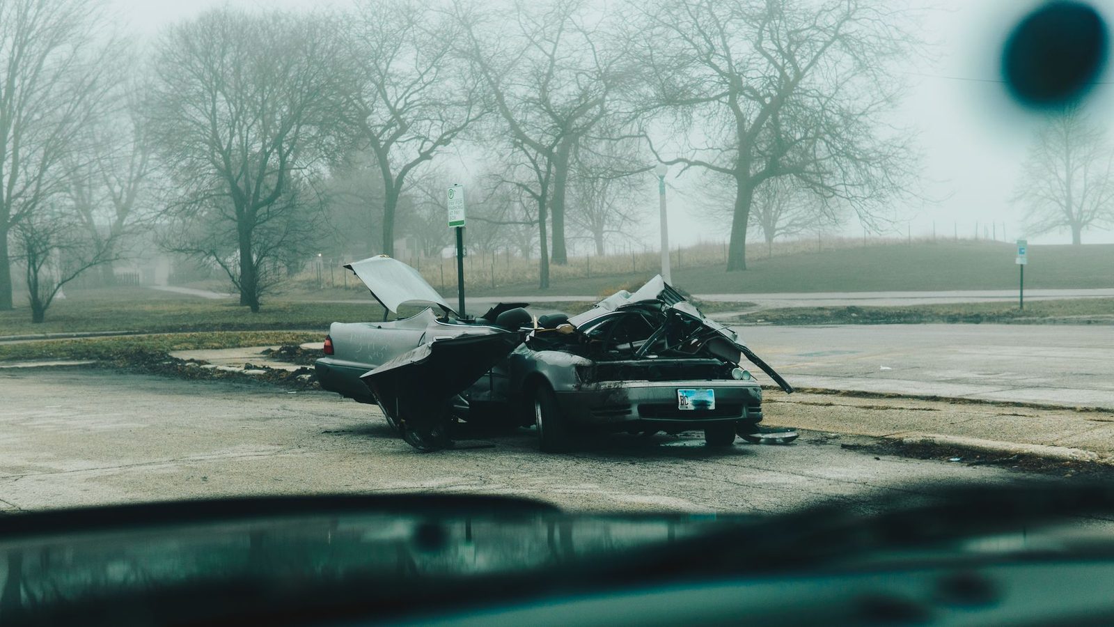 Severely damaged car on a deserted street on a foggy morning.