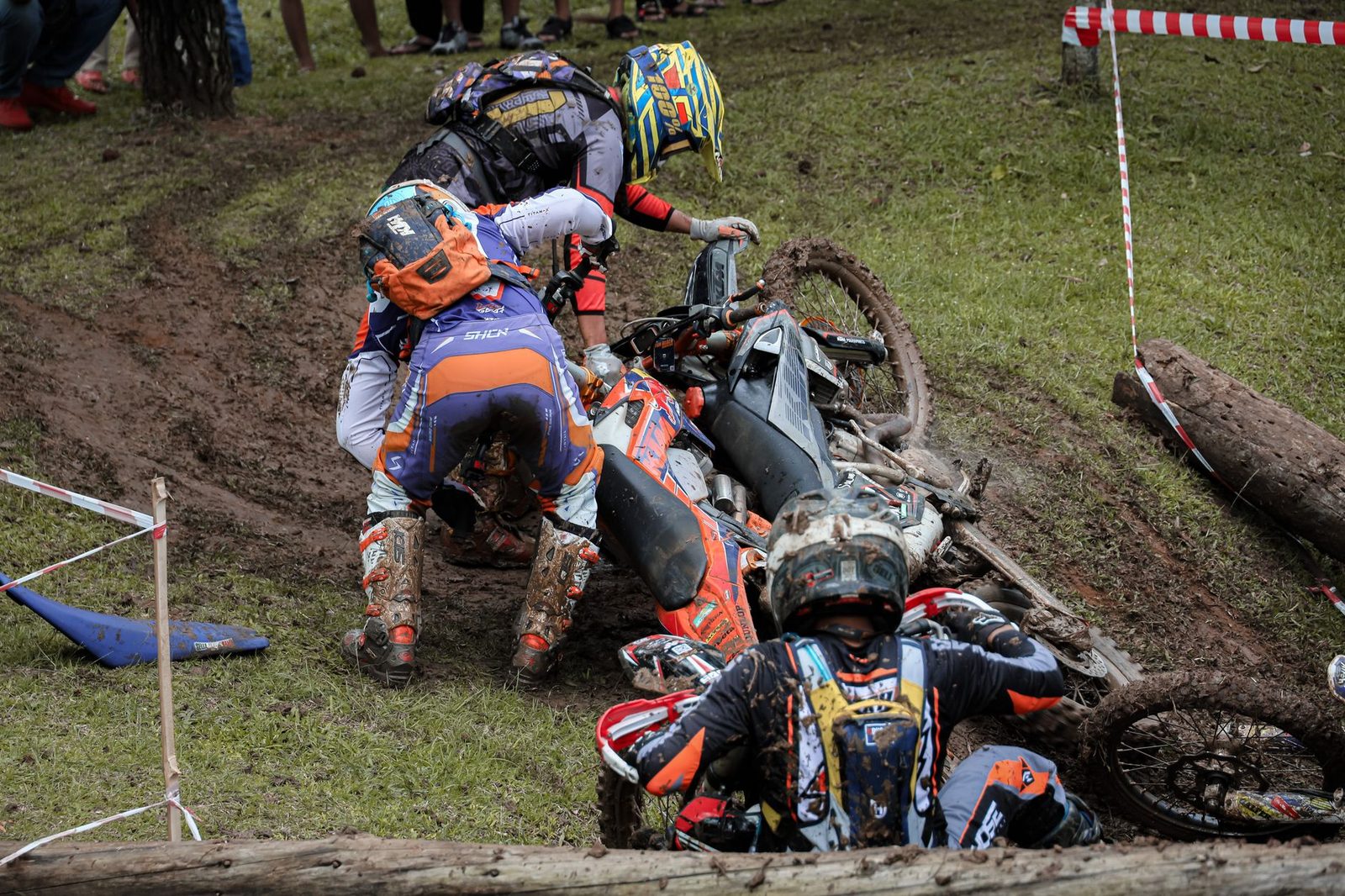 Three motorcycle riders after a crash on a muddy track in Bandung, Indonesia.
