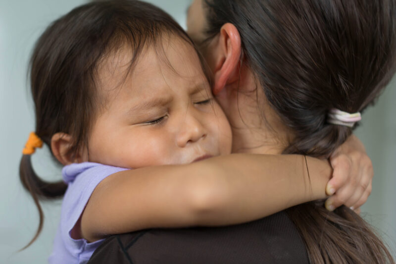 Child hugging her mother for comfort and support. Family love and affection.